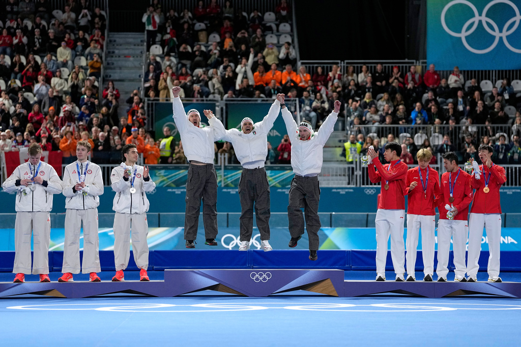 Team Italy, center and goal medal, team USA, left and silver medal, and team China celebrate on the podium of the men's team pursuit speedskating race at the 2026 Winter Olympics, in Milan, Italy, Tuesday, Feb. 17, 2026. (AP Photo/Ben Curtis)