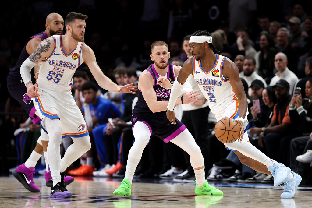 Oklahoma City Thunder guard Shai Gilgeous-Alexander, right, works around Minnesota Timberwolves guard Donte Divincenzo, second from right, during the first half of an NBA basketball game Friday, Dec. 19, 2025, in Minneapolis. (AP Photo/Matt Krohn)