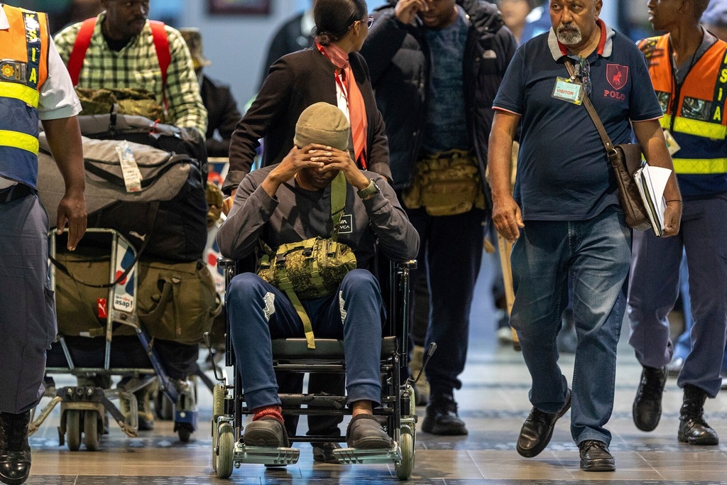 South African men who were allegedly tricked into fighting for Russia in the war in Ukraine are escorted by police officers as they arrive at King Shaka International Airport in Durban, South Africa, Wednesday, Feb. 25, 2026. (AP Photo/Str)