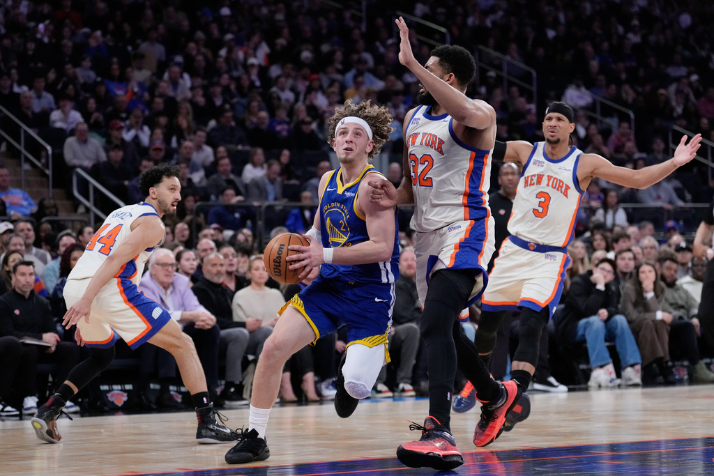 Golden State Warriors' Brandin Podziemski, second from left, drives to the basket through New York Knicks defenders during the first half of an NBA basketball game Sunday, March 15, 2026, in New York. (AP Photo/Seth Wenig)
