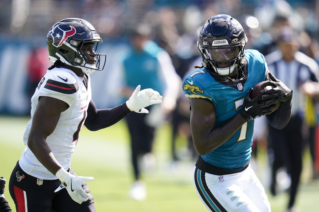 Jacksonville Jaguars wide receiver Brian Thomas Jr., right, holds the ball after making a catch as Houston Texans cornerback Kamari Lassiter tries to push him out of bounds during the second half of an NFL football game Sunday, Sept. 21, 2025, in Jacksonville, Fla. (AP Photo/John Raoux)
