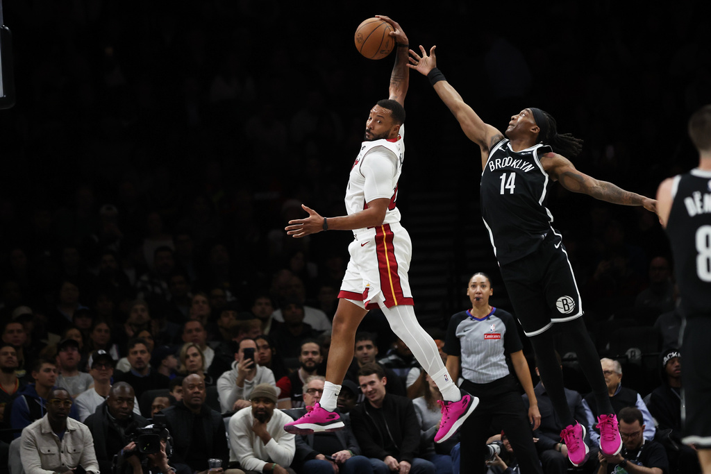 Miami Heat guard Norman Powell, left, grabs a rebound over Brooklyn Nets guard Terance Mann (14) during the first half of an NBA basketball game, Thursday, Dec. 18, 2025, in New York. (AP Photo/Heather Khalifa)