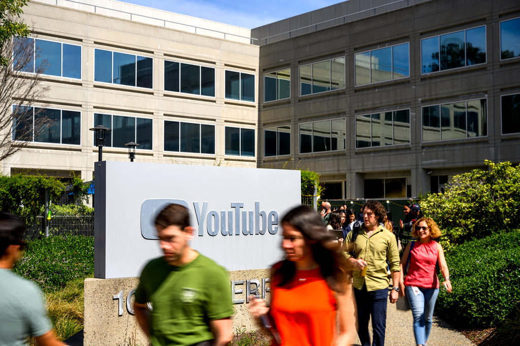 Workers pass a sign at YouTube headquarters on Thursday, March 26, 2026, in San Bruno, Calif. (AP Photo/Noah Berger)