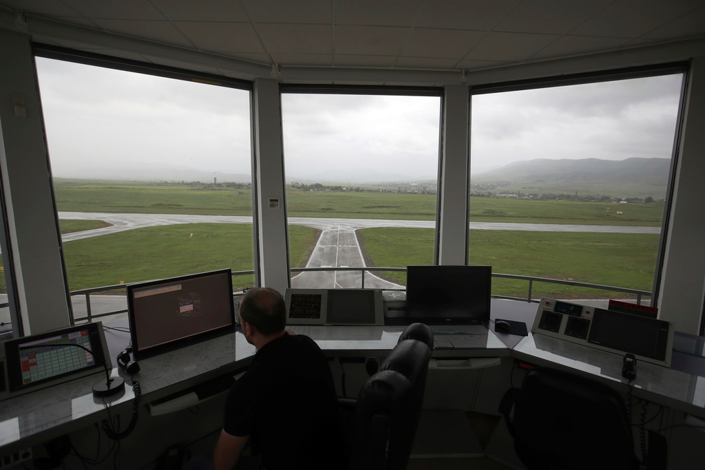 FILE - In this Friday, May 11, 2018 photo, a man watches a screen atop the air-traffic control tower at the empty Stepanakert airport. (AP Photo/Thanassis Stavrakis, File)