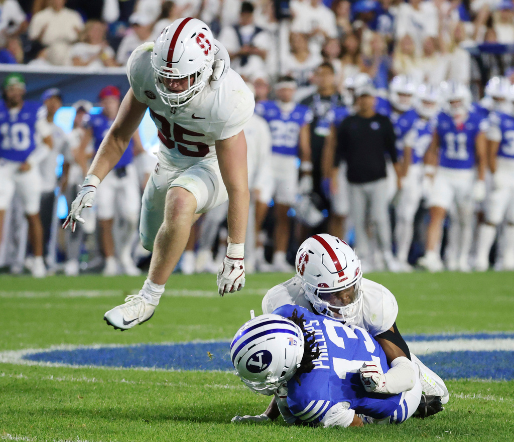 Stanford cornerback Collin Wright, right, tackles BYU wide receiver Jojo Phillips during the first half of an NCAA college football game Saturday Sept. 6, 2025, in Provo, Utah. Stanford linebacker Matt Rose leaps over them. (AP Photo/Jeffrey D. Allred)