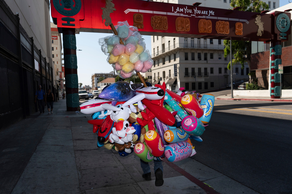 FILE - A street vendor carries cotton candy and inflatable toys near MacArthur Park in Los Angeles, an area targeted in recent ICE raids, on July 19, 2025. (AP Photo/Jae C. Hong, File)