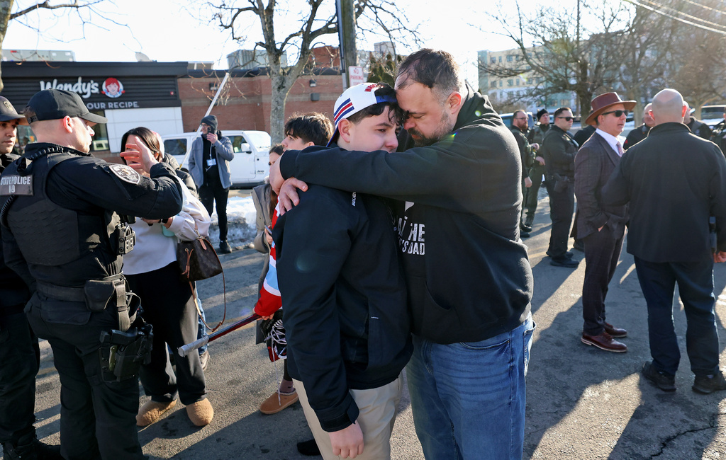 A father hugs his son outside of the Lynch Arena in Pawtucket, R.I., after a shooting at the ice rink, Monday, Feb. 16, 2026. (AP Photo/Mark Stockwell)