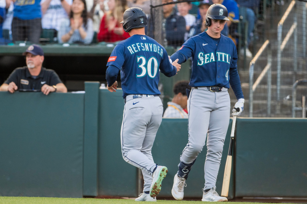 Seattle Mariners' Rob Refsnyder (30) celebrates with Colt Emerson (4) after Refsnyder scored during the second inning of a baseball game against the Athletics in West Sacramento, Calif., Tuesday, May 26, 2026. (AP Photo/Nic Coury)