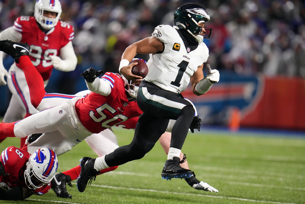 Philadelphia Eagles' Jalen Hurts, right, scrambles past Buffalo Bills' Greg Rousseau during the first half of an NFL football game, Sunday, Dec. 28, 2025, in Buffalo, N.Y. (AP Photo/Gene J. Puskar)