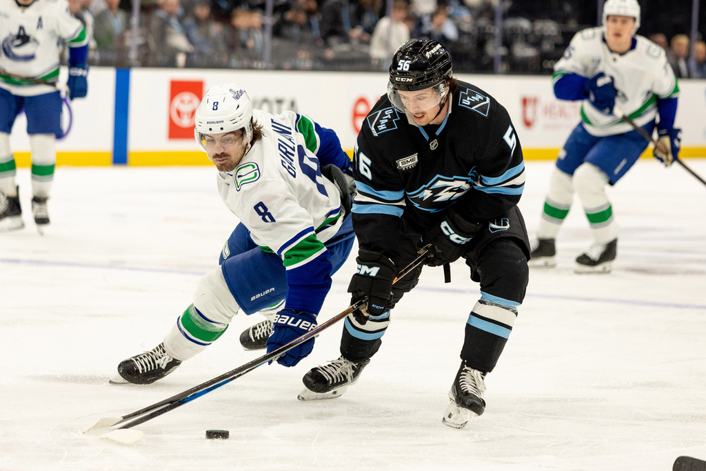 Vancouver Canucks right wing Conor Garland (8) fights for the puck against Utah Mammoth right wing Kailer Yamamoto (56) during the second period of an NHL hockey game Monday, Feb. 2, 2026, in Salt Lake City. (AP Photo/Melissa Majchrzak)