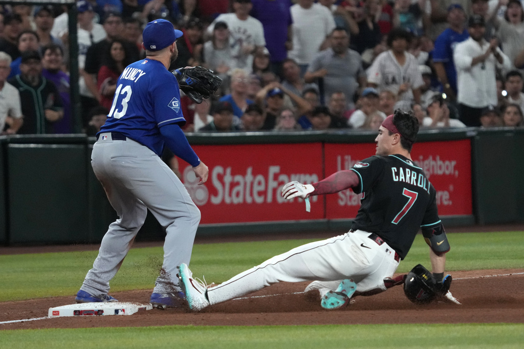 Arizona Diamondbacks' Corbin Carroll (7) slides into thirdbase after hitting an RBI triple under the tag by Los Angeles Dodgers third baseman Max Muncy in the ninth inning of a baseball game, Saturday, Aug. 8, 2026, in Phoenix. (AP Photo/Rick Scuteri)