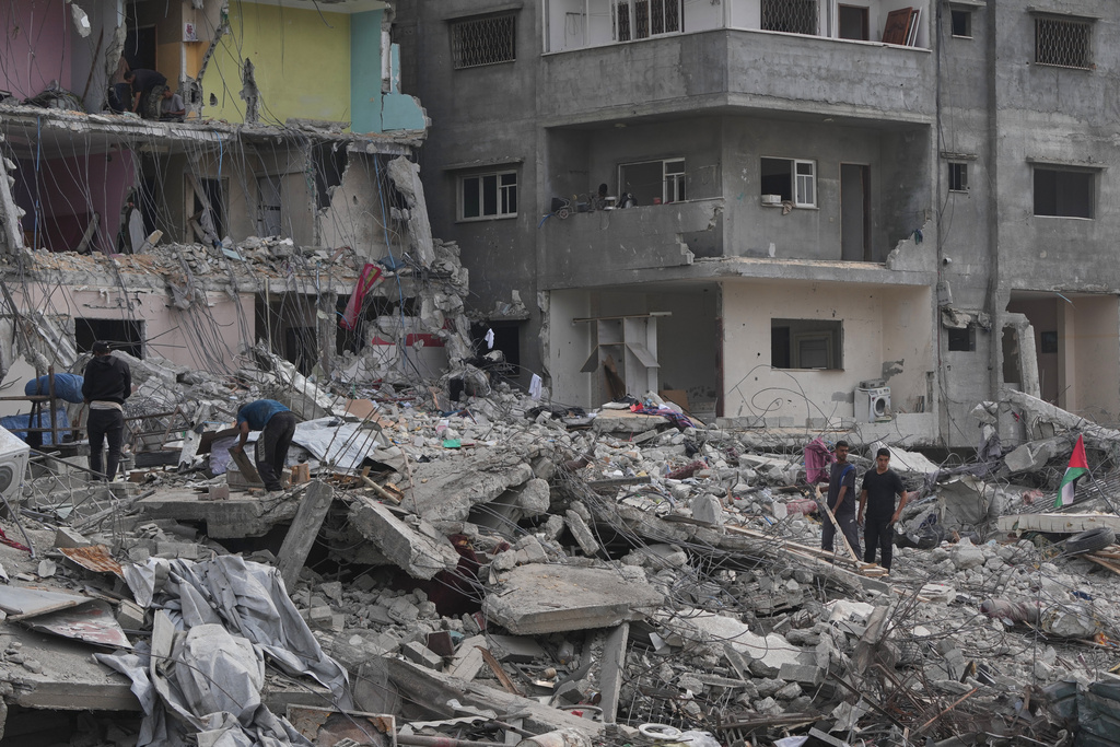 Displaced Palestinians inspect the remains of their destroyed homes in Gaza City, Sunday, Oct. 12, 2025, after Israel and Hamas agreed to a pause in their war and the release of the remaining hostages. (AP Photo/Abdel Kareem Hana)