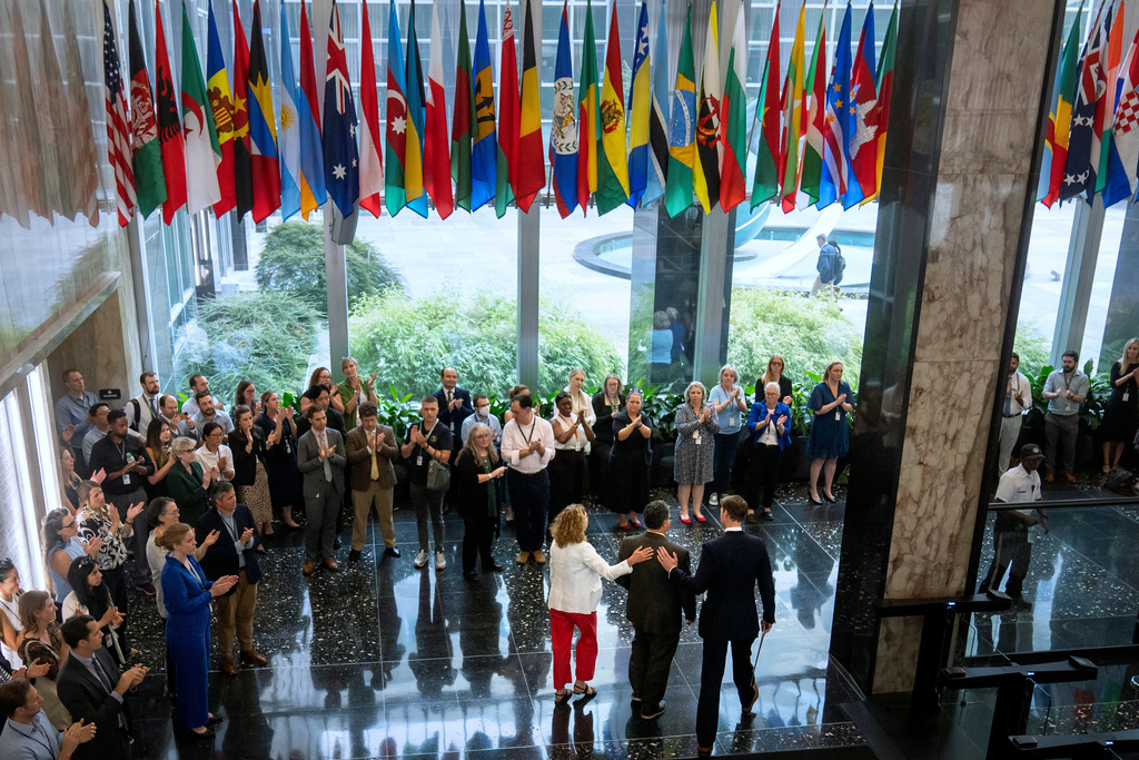 FILE - State Department employees applaud as their colleagues walk through the lobby of the State Department headquarters in the Harry S. Truman Building, July 11, 2025, in Washington. (AP Photo/Mark Schiefelbein, file)