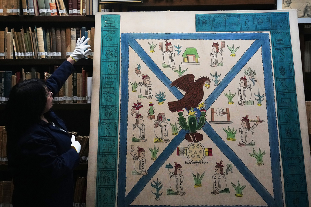 Rosalba Sanchez Flores, a historian at the National Museum of Anthropology in Mexico City, points to the details of Mexico's coat of arms as depicted in the Codex Mendoza, Friday, Nov. 14, 2025. (AP Photo/Claudia Rosel)