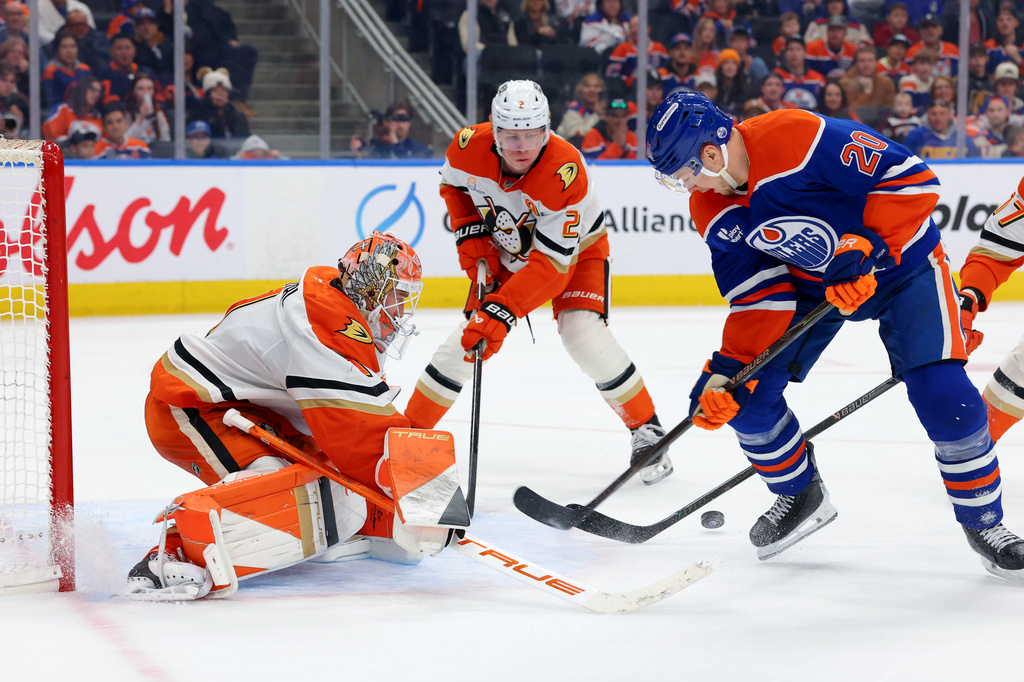 Anaheim Ducks goalie Lukas Dostal (1), Jackson LaCombe (2) and Edmonton Oilers' Curtis Lazar (20) scramble for the puck during the second period of an NHL hockey game in Edmonton, Alberta, Saturday March 28, 2026. (James Maclennan/The Canadian Press via AP)