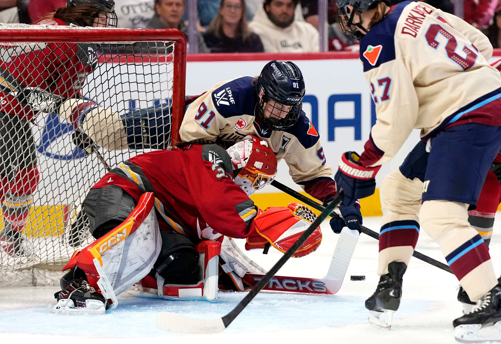 Montreal Victoire's Maggie Flaherty (91) leans over Ottawa Charge goaltender Gwyneth Philips, center bottom, as she looks for the puck at the net during the first period of Game 3 in the PWHL Walter Cup finals hockey series in Ottawa, Ontario, Monday May 18, 2026. (Justin Tang/The Canadian Press via AP)