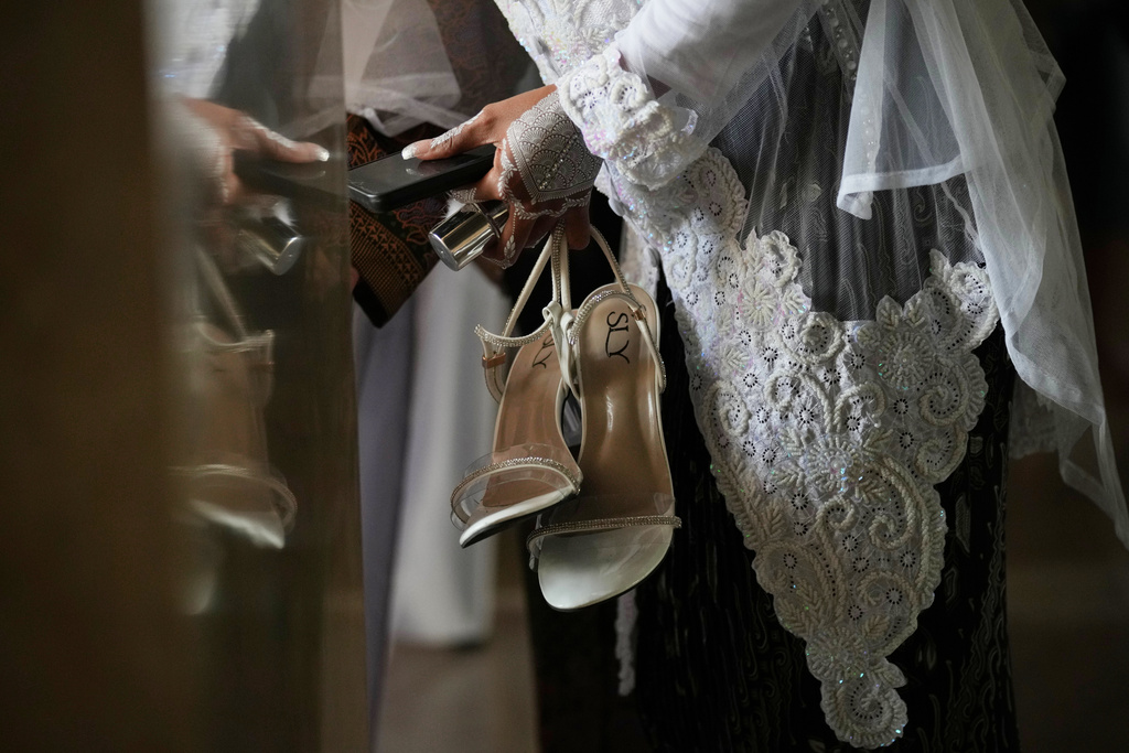 A bride holds her footwear during a mass wedding ceremony at Istiqlal Mosque in Jakarta, Indonesia, Wednesday, Dec. 3, 2025. (AP Photo/Tatan Syuflana)