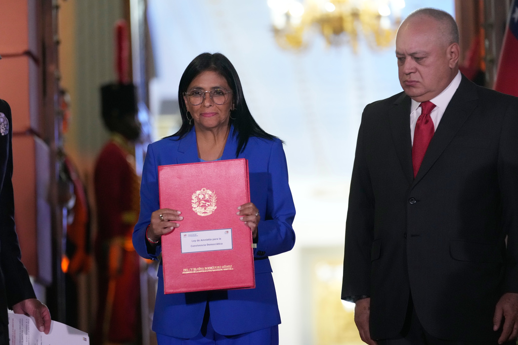 Venezuelan acting President Delcy Rodriguez holds up an amnesty bill approved by the National Assembly alongside Interior Minister Diosdado Cabello at Miraflores Palace in Caracas, Venezuela, Thursday, Feb. 19, 2026. (AP Photo/Ariana Cubillos)