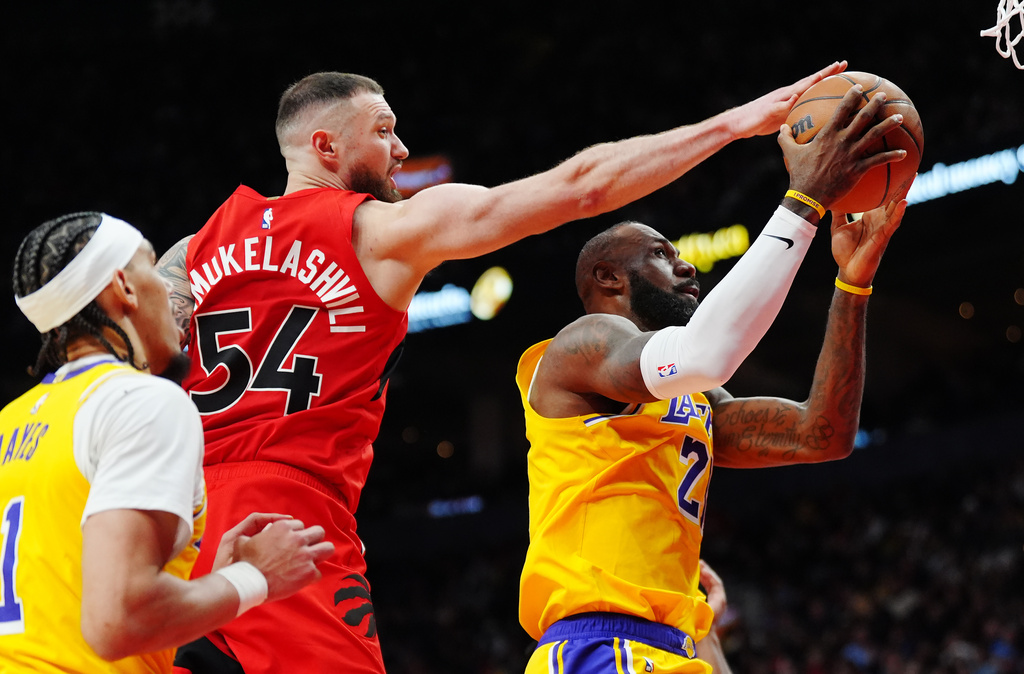 Los Angeles Lakers' LeBron James (right) drives to the basket as Toronto Raptors' Sandro Mamukelashvili (54) defends during second half NBA basketball action in Toronto on Thursday, Dec. 4, 2025. THE CANADIAN PRESS/Frank Gunn/The Canadian Press via AP)