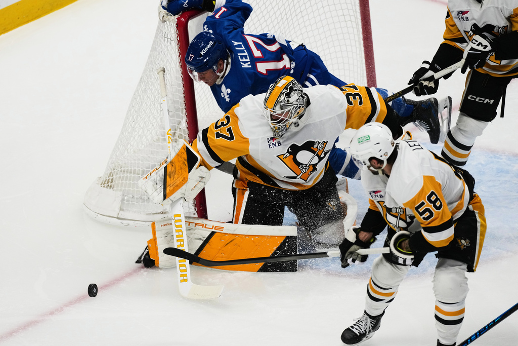 Pittsburgh Penguins goalie Arturs Silvos (37) pins Colorado Avalanche center Parker Kelly (17) to the net as Penguins defenseman Kris Letang (58) looks to clear the puck in the first period of an NHL hockey game Monday, March 16, 2026, in Denver. (AP Photo/David Zalubowski)