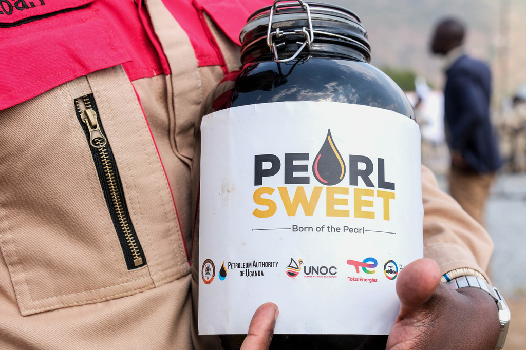 A worker holds a container with a crude oil sample at the Kingfisher oil field, operated by China National Offshore Oil Corporation (CNOOC), near Hoima, Uganda, Wednesday, Sept. 2, 2026. (AP Photo/Hajarah Nalwadda)