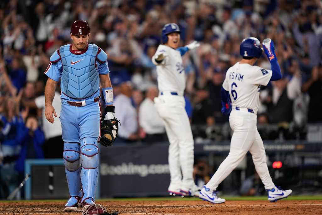 Philadelphia Phillies catcher J.T. Realmuto, left, walks off the field after Los Angeles Dodgers' Hyeseong Kim, right, scored the game-winning run on a ground ball from Andy Pages and throwing error from Phillies pitcher Orion Kerkering during the eleventh inning in Game 4 of baseball's National League Division Series Thursday, Oct. 9, 2025, in Los Angeles. (AP Photo/Mark J. Terrill)