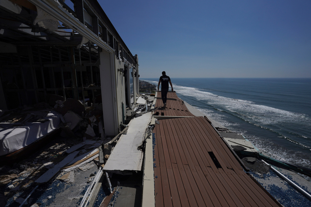 FILE - A man walks alongside damaged apartments in the aftermath of Hurricane Otis, in the Diamonds subdivision of Acapulco, Mexico, Nov. 9, 2023. (AP Photo/Marco Ugarte, File)