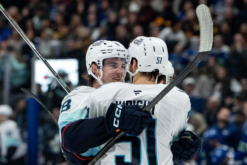Seattle Kraken's Cale Fleury (8) celebrates after his goal against the Vancouver Canucks with teammate Shane Wright (51) during the first period of an NHL game in Vancouver, British Columbia, Friday, Jan. 2, 2026. (Ethan Cairns/The Canadian Press via AP)