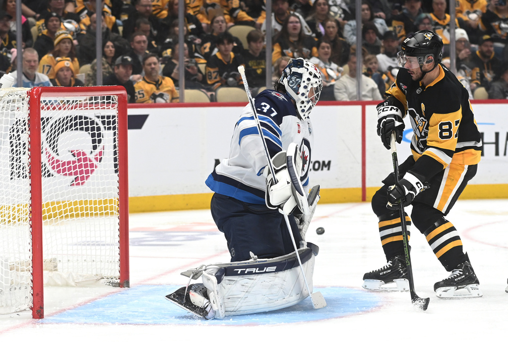 Pittsburgh Penguins center Sidney Crosby (87) pressures Winnipeg Jets goalie Connor Hellebuyck (37) during the second period of an NHL game, Saturday, March 21, 2026, in Pittsburgh. (AP Photo/Philip G. Pavely)