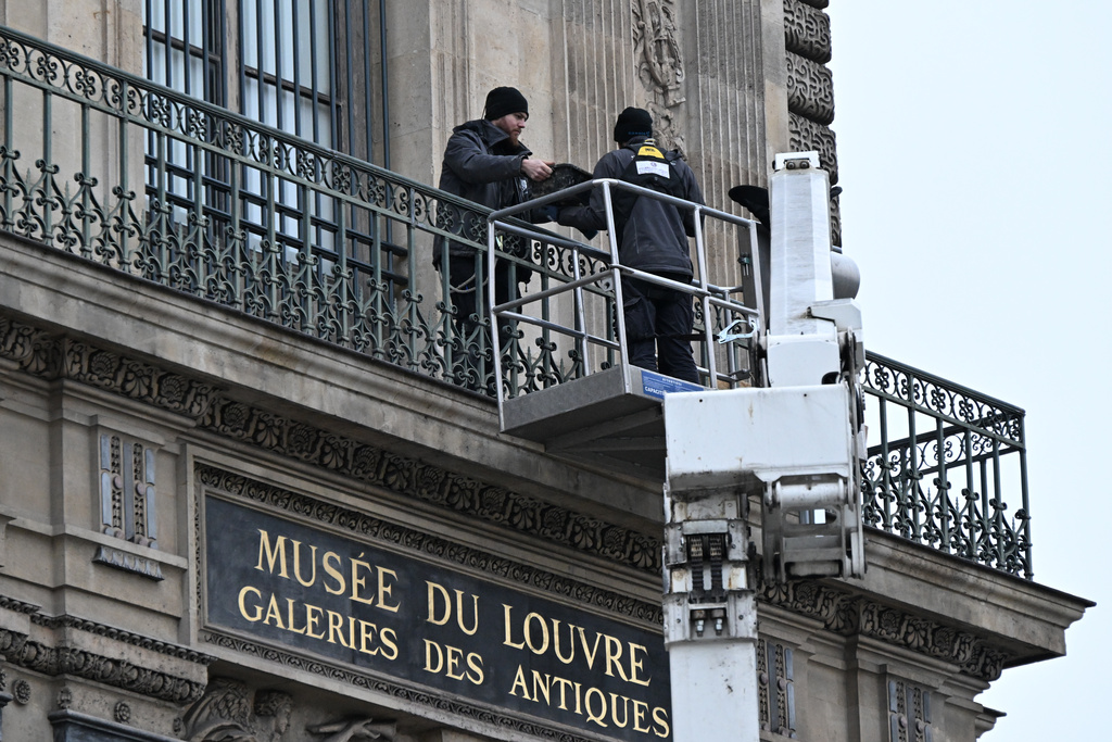 Workers install metal security bars over the window where thieves broke into the Louvre museum on Oct.19, Tuesday Dec.23, 2025 in Paris. (AP Photo/Emma Da Silva)