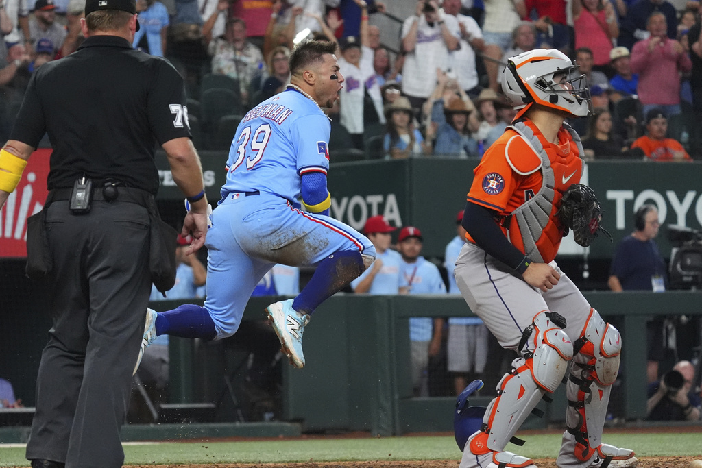 Texas Rangers' Cody Freeman (39) reacts to scoring on a double by teammate Josh Jung as Houston Astros catcher Yainer Diaz, right, and umpire Mike Muchlinski, left, look on during the sixth inning of a baseball game, Sunday, Sept. 7, 2025, in Arlington, Texas. (AP Photo/LM Otero)