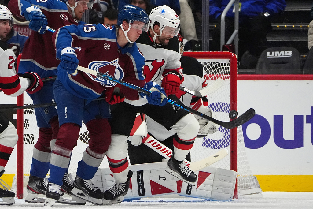 Colorado Avalanche left wing Victor Olofsson, front, redirects a shot past New Jersey Devils center Luke Glendening in the second period of an NHL hockey game, Tuesday, Oct. 28, 2025, in Denver. (AP Photo/David Zalubowski)