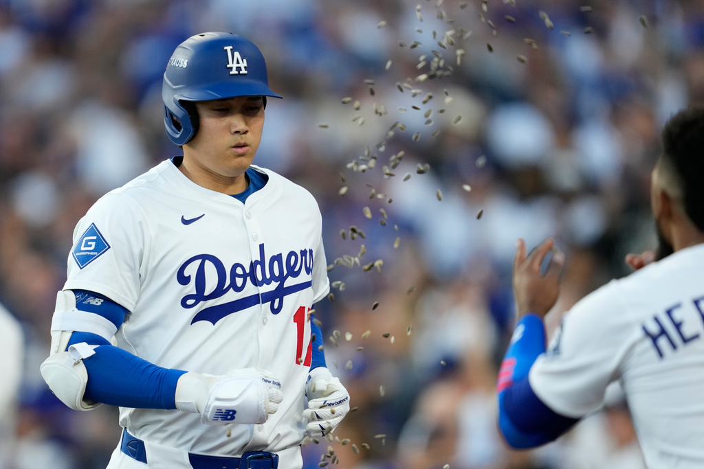 El dominicano Teoscar Hernández, de los Dodgers de Los Ángeles, arroja semillas de girasol al japonés Shohei Ohtani, luego de que conectó su primero de tres jonrones en el cuarto juego de la Serie de Campeonato de la Liga Nacional ante los Cerveceros de Milwaukee, el viernes 17 de octubre de 2025 (AP Foto/Ashley Landis)