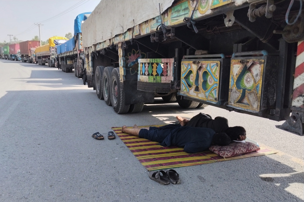 Drivers sleep under a truck loaded with goods for Afghanistan park along a highway following border closed due to Afghan and Pakistani forces exchange cross border firing, in Jamrud, in the district Khyber, Pakistan, Monday, Oct. 13, 2025. (AP Photo/Qazi Rauf)