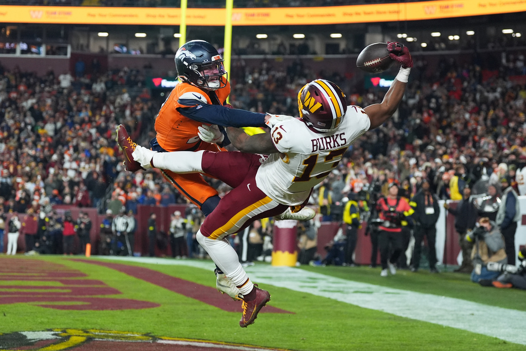 FILE - Washington Commanders wide receiver Treylon Burks (13) catches a touchdown pass as Denver Broncos cornerback Riley Moss, left, defends during the second half of an NFL football game Sunday, Nov. 30, 2025, in Landover, Md. (AP Photo/Stephanie Scarbrough, File)