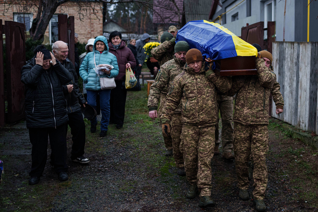 An honor guard carries the coffin of Ruslan Zhygunov, a Ukrainian serviceman, who was killed at the frontline near Rusyn Yar village, during his funeral ceremony in Hostomel, Ukraine, on Saturday, Nov. 22, 2025. (AP Photo/Evgeniy Maloletka)