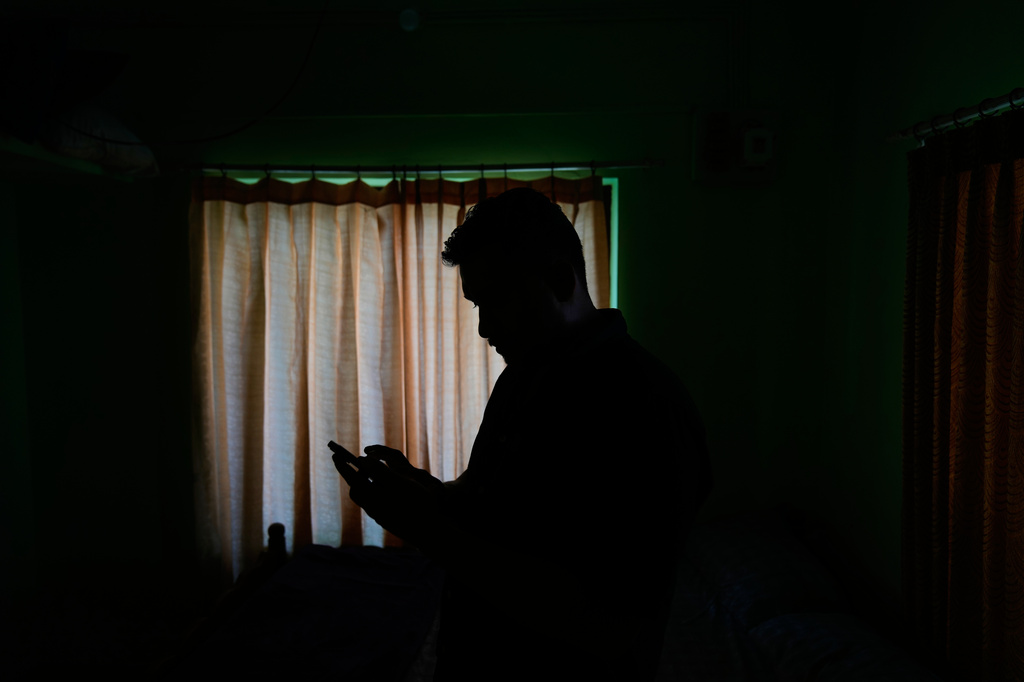 Safeer Mohammed Koorimannil looks at a photograph on his mobile phone of the injuries he said he sustained when his employer at the Tai Chang scam compound in Myanmar beat him for underperformance in Sulthan Bathery in the southern state of Kerala, India, Thursday, March 12, 2026. (AP Photo/Manish Swarup)