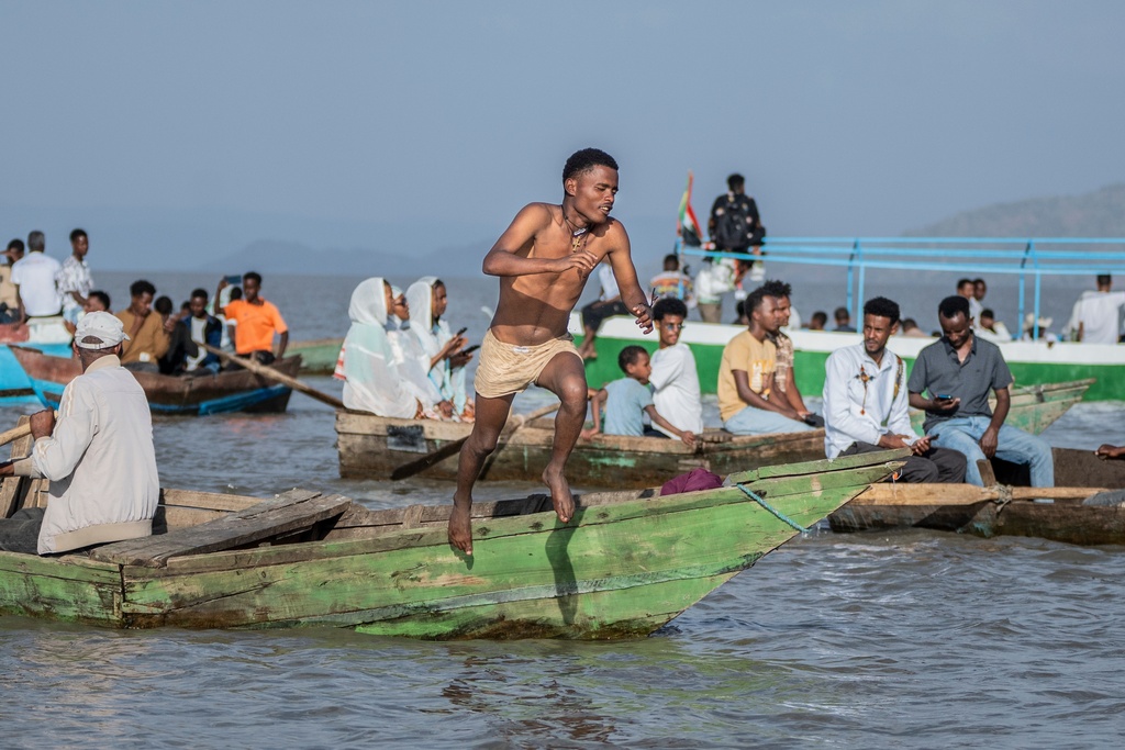 An Ethiopian orthodox believer jumps from a boat as faithful celebrate Timket, the Ethiopian Epiphany, on lake Dembel, in Batu, Ethiopia, Sunday, Jan. 18, 2026. (AP Photo/Amanuel Sileshi)