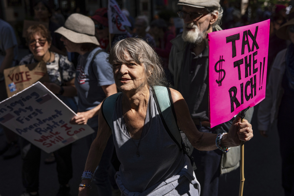 A woman carrying a "Tax the rich" sign marches through Manhattan at the "Make Billionaires Pay" climate protest, Saturday, Sept. 20, 2025, in New York. (AP Photo/Angelina Katsanis)