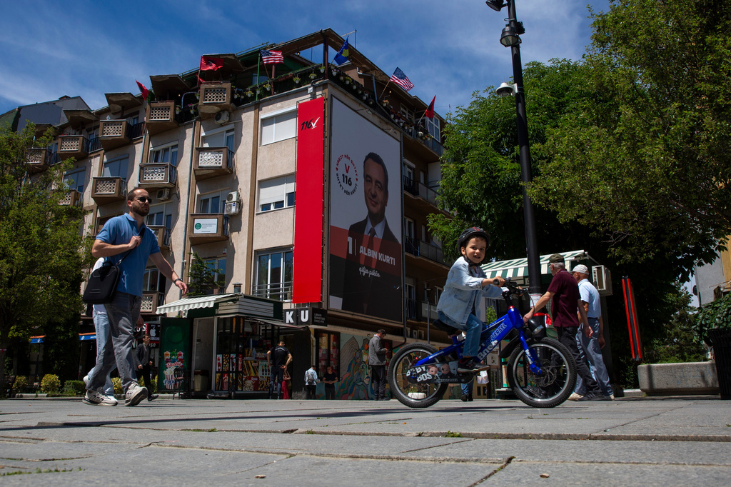 People walk past a giant election poster of acting prime minister Albin Kurti in capital Pristina, Kosovo, Friday, June 5, 2026, ahead of snap parliamentary elections on June 7. (AP Photo/Visar Kryeziu)