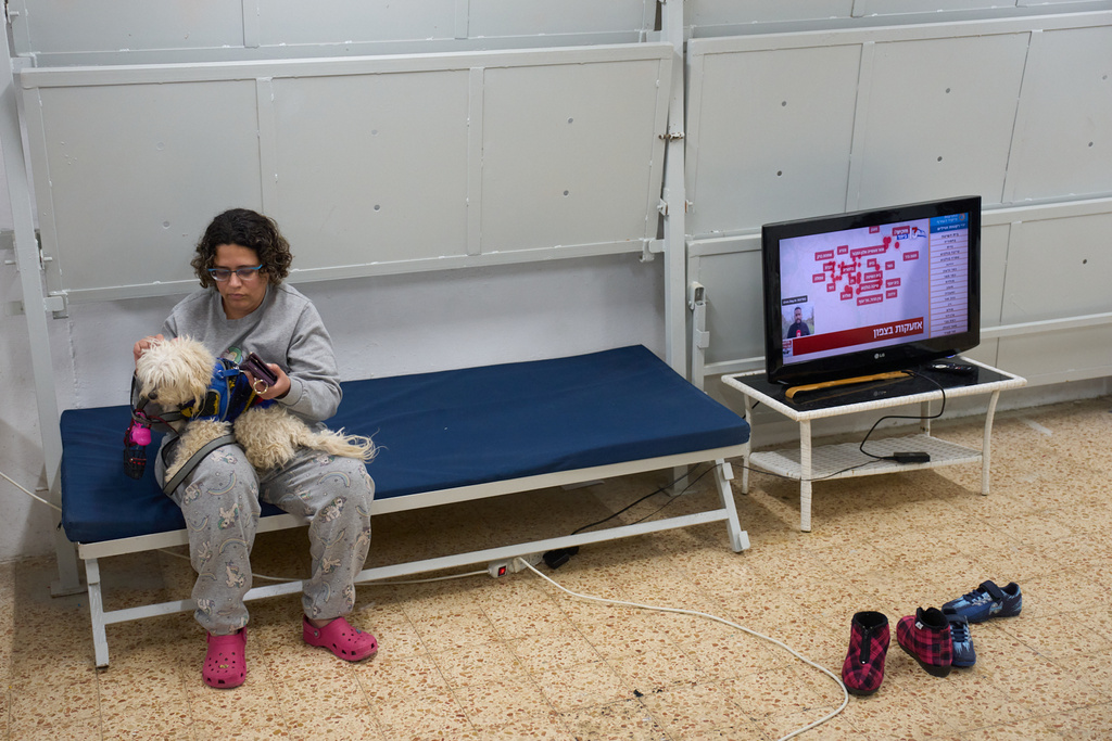 Nofar Eliash grasps her dog as she takes shelter while air raid sirens warn of incoming Iranian and Hezbollah missile strikes in Kiryat Shmona, northern Israel, Monday, March 16, 2026. (AP Photo/Ariel Schalit)