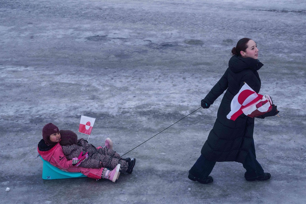 A woman pulls her children on a sled during a protest against Trump's policy towards Greenland in front of the US consulate in Nuuk, Greenland, Saturday, Jan. 17, 2026. (AP Photo/Evgeniy Maloletka)