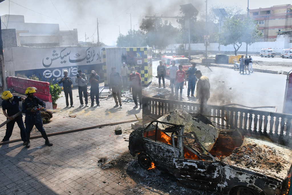 Firefighters pour water on a burning car, which was set on fire by protestors close to the U.S. Consulate in Karachi, Pakistan, Sunday, March 1, 2026. (AP Photo/Ali Raza)