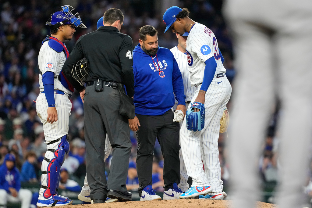 Chicago Cubs starting pitcher Edward Cabrera, right, is checked by a team trainer after an injury during the fifth inning of a baseball game against the Colorado Rockies in Chicago, Tuesday, June 16, 2026. (AP Photo/Nam Y. Huh)