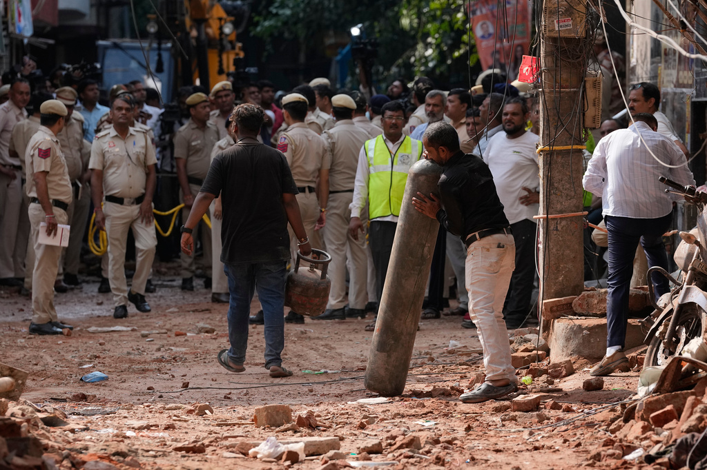 A rescue worker carries a cylinder at the site of a collapsed building in New Delhi, India, Monday, Sept. 7, 2026. (AP Photo/Manish Swarup)