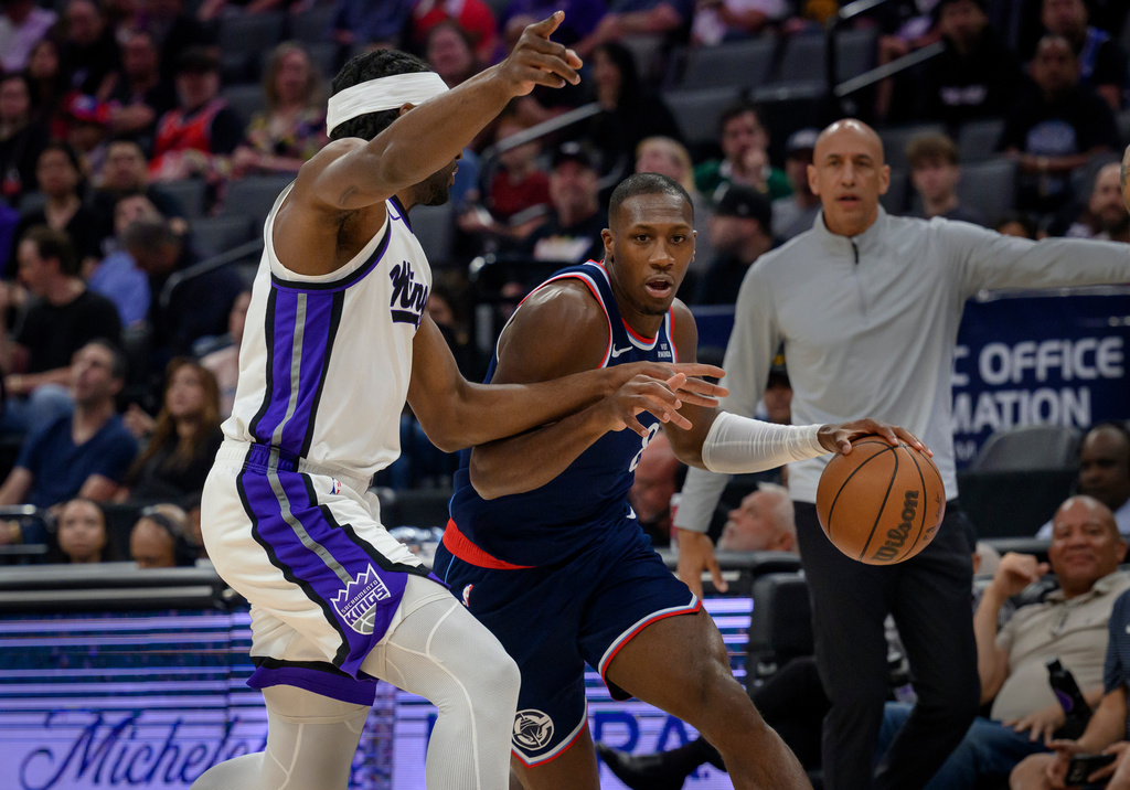 Los Angeles Clippers guard Kris, center, Dunn is guarded by Sacramento Kings forward Precious Achiuwa during the first half of an NBA basketball game in Sacramento, Calif., Sunday, April 5, 2026. (AP Photo/Randall Benton)