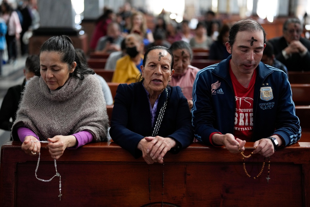 FILE - Catholics pray the rosary while a priest marks people's foreheads with ashes during Ash Wednesday Mass at the Church of the Divine Child in Bogota, Colombia, Wednesday, Feb. 14, 2024. (AP Photo/Fernando Vergara, File)