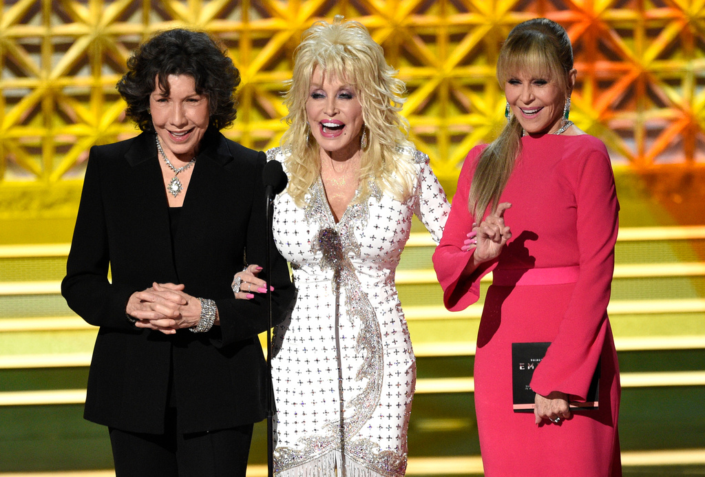 FILE - Dolly Parton, center, stands on stage with Lily Tomlin, left, and Jane Fonda at the 69th Primetime Emmy Awards in Los Angeles, Sept. 17, 2017. (Photo by Chris Pizzello/Invision/AP)