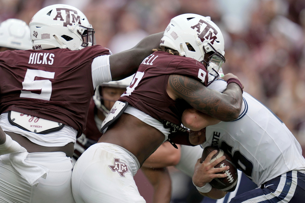 Texas A&M defensive tackle DJ Hicks (5) and defensive end Cashius Howell (9) sack Utah State quarterback Bryson Barnes (16) during the second quarter of an NCAA college football game Saturday, Sept. 6, 2025, in College Station, Texas. (AP Photo/Sam Craft)