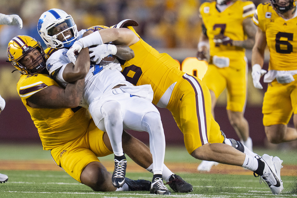 Minnesota defensive linemen Deven Eastern, left, and Lucas Finnessy, front right, sack Buffalo quarterback Ta'Quan Roberson, second from left, in the second quarter of an NCAA college football game in Minneapolis, Thursday, Aug. 28, 2025. (Alex Kormann/Star Tribune via AP)